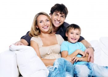 Happy young family with child siting on white sofa isolated